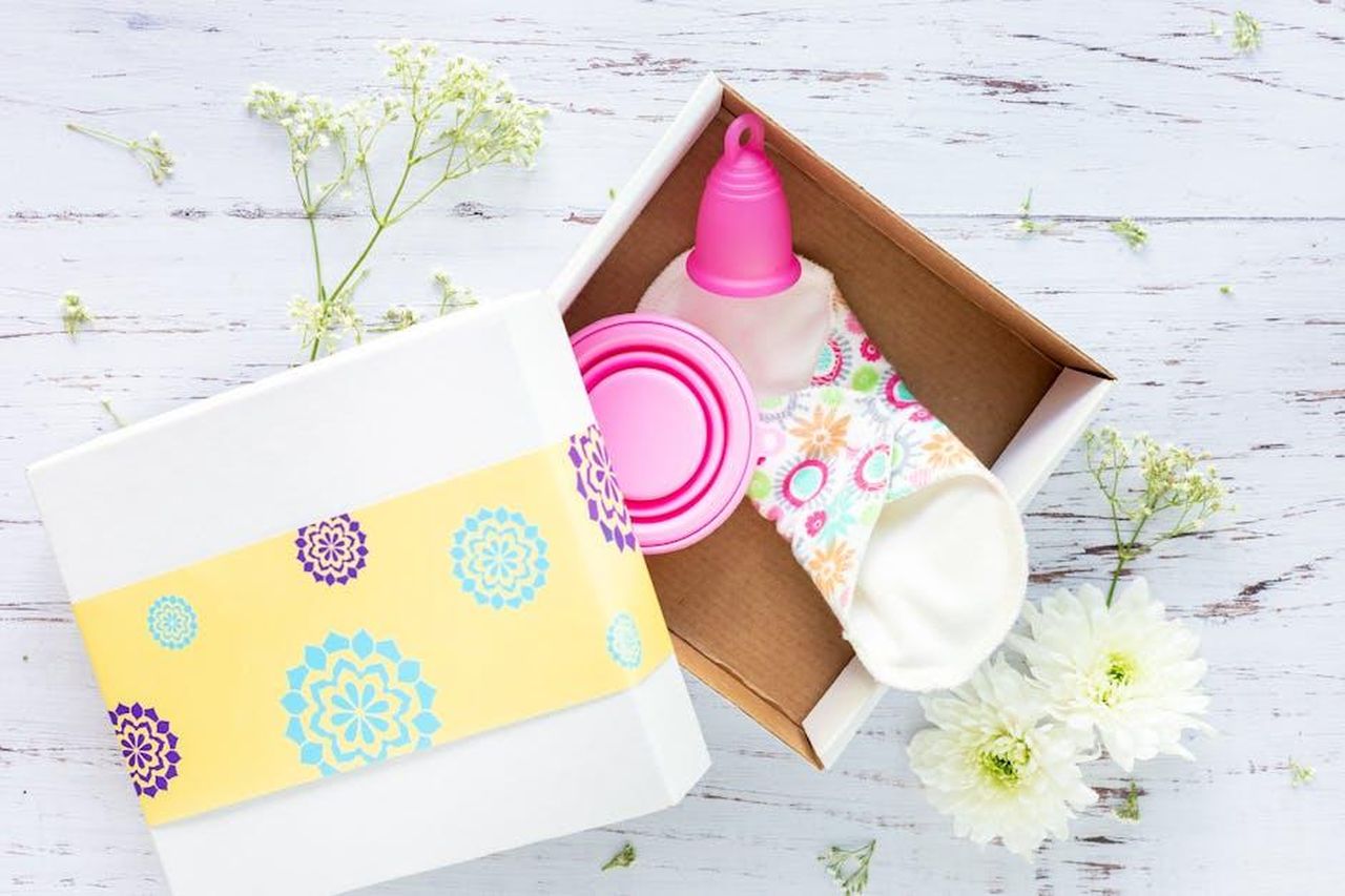 Source: Vanessa Ramirez - pexels - Brightly decorated gift box containing reusable menstrual cup and pads on a rustic background.