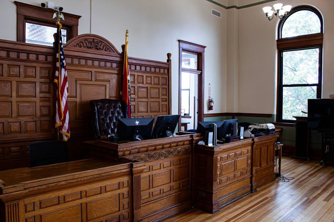 Source: Zachary Caraway - pexels - Interior view of an American courthouse in Kirksville, Missouri, featuring a judge's desk and flags.