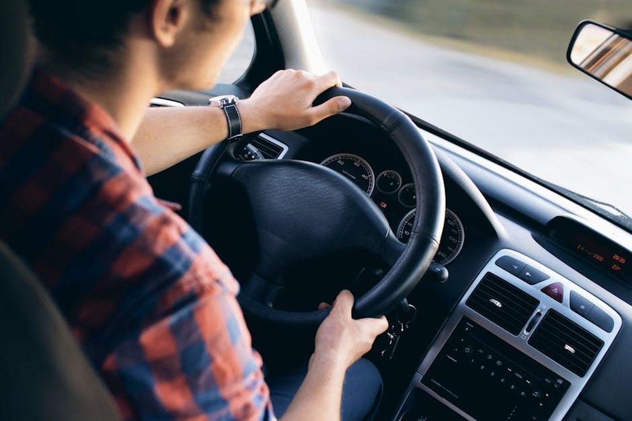 Source: JESHOOTS.com - pexels - Close-up view of a man driving a modern car, showing dashboard and steering details.