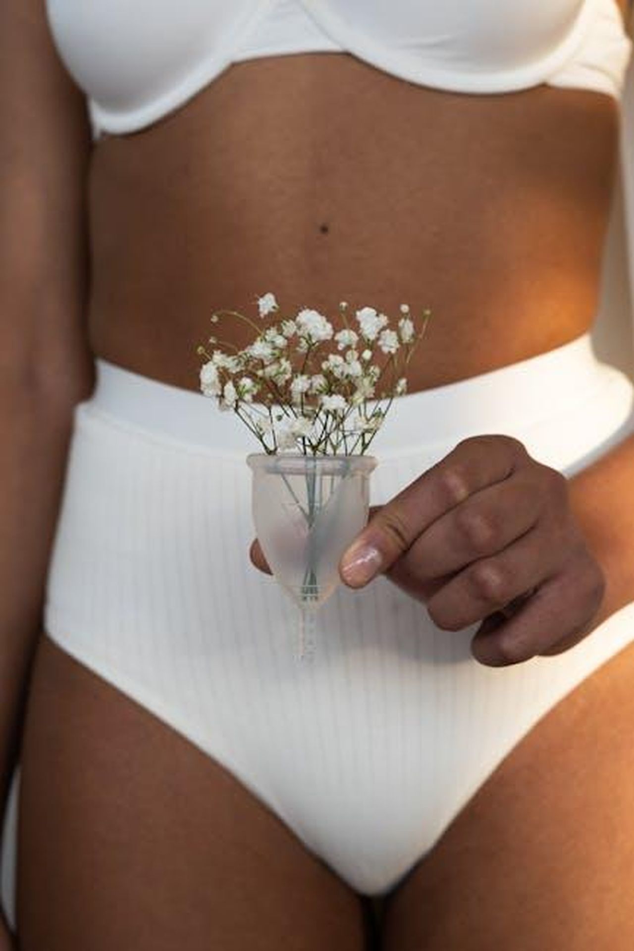 Source: cottonbro studio - pexels - Close-up of a woman holding a menstrual cup filled with flowers, promoting eco-friendly feminine hygiene.