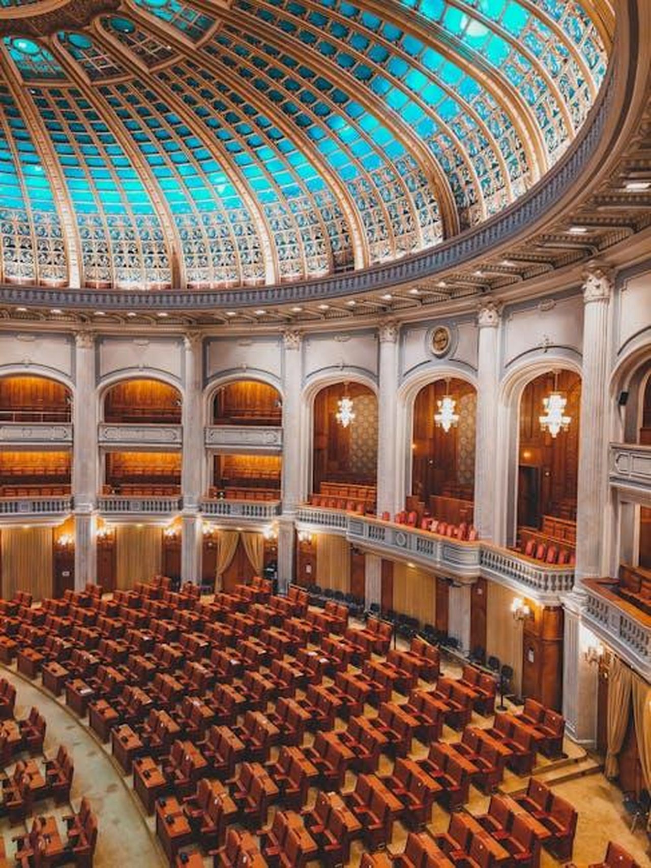 Source: Czapp Árpád - pexels - Majestic view of an ornate parliamentary chamber with a striking turquoise dome and plush seating.