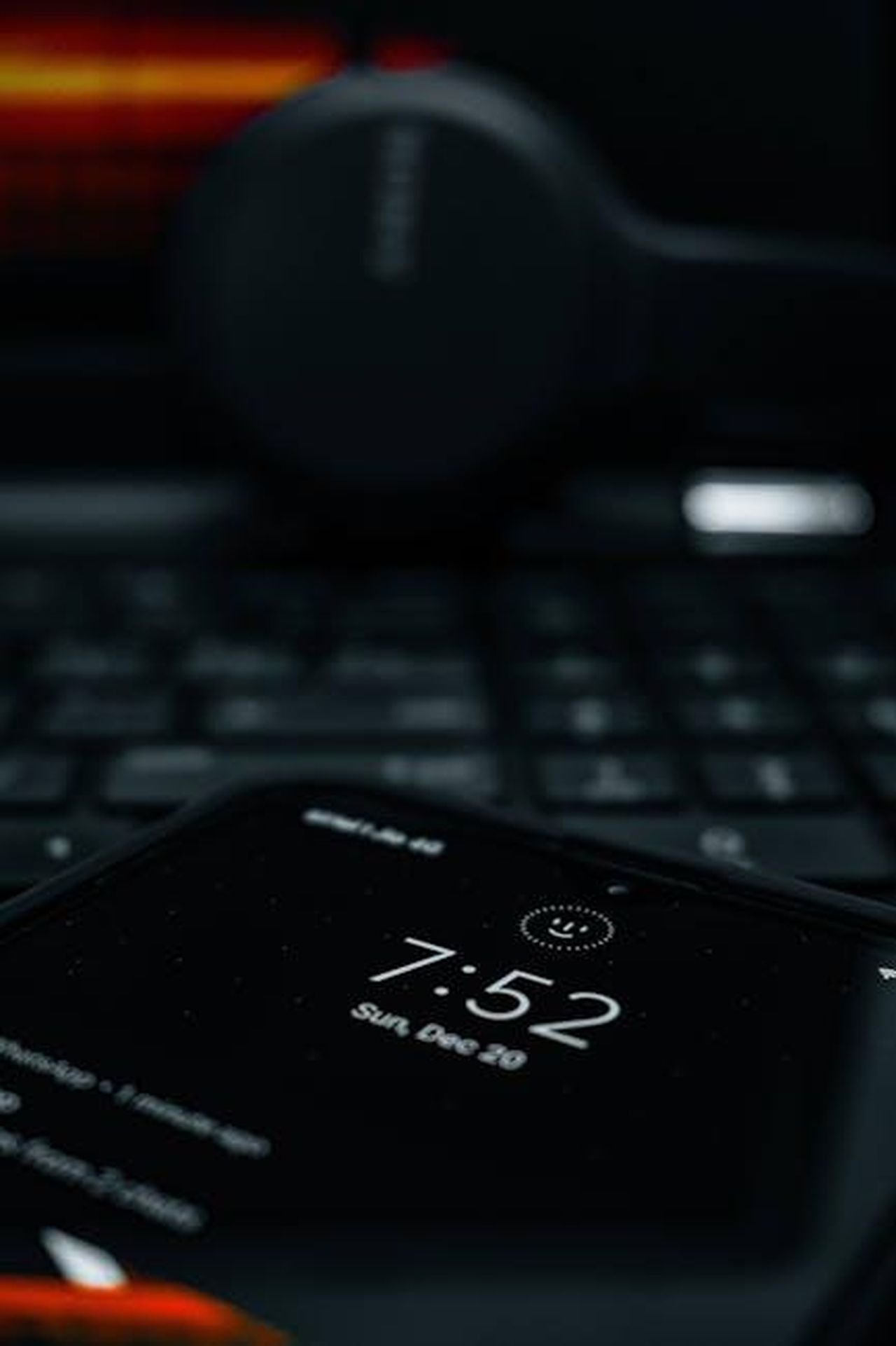 Source: Shivam - pexels - A smartphone showing time with a blurred laptop and headphones in the background, creating a tech-focused scene.