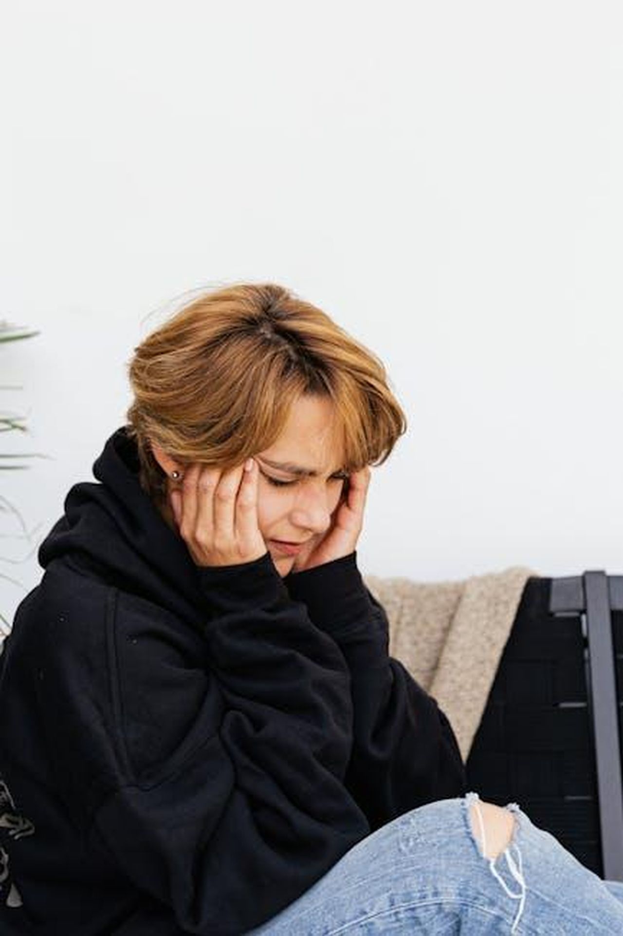 Source: Photo By: Kaboompics.com - pexels - Adult woman sitting with eyes closed, showing headache or stress symptoms indoors.