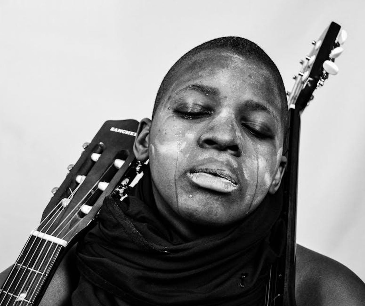 Source: EZA HELDER NGAM - pexels - Close-up black and white portrait of a person reflecting deep emotion with a guitar.