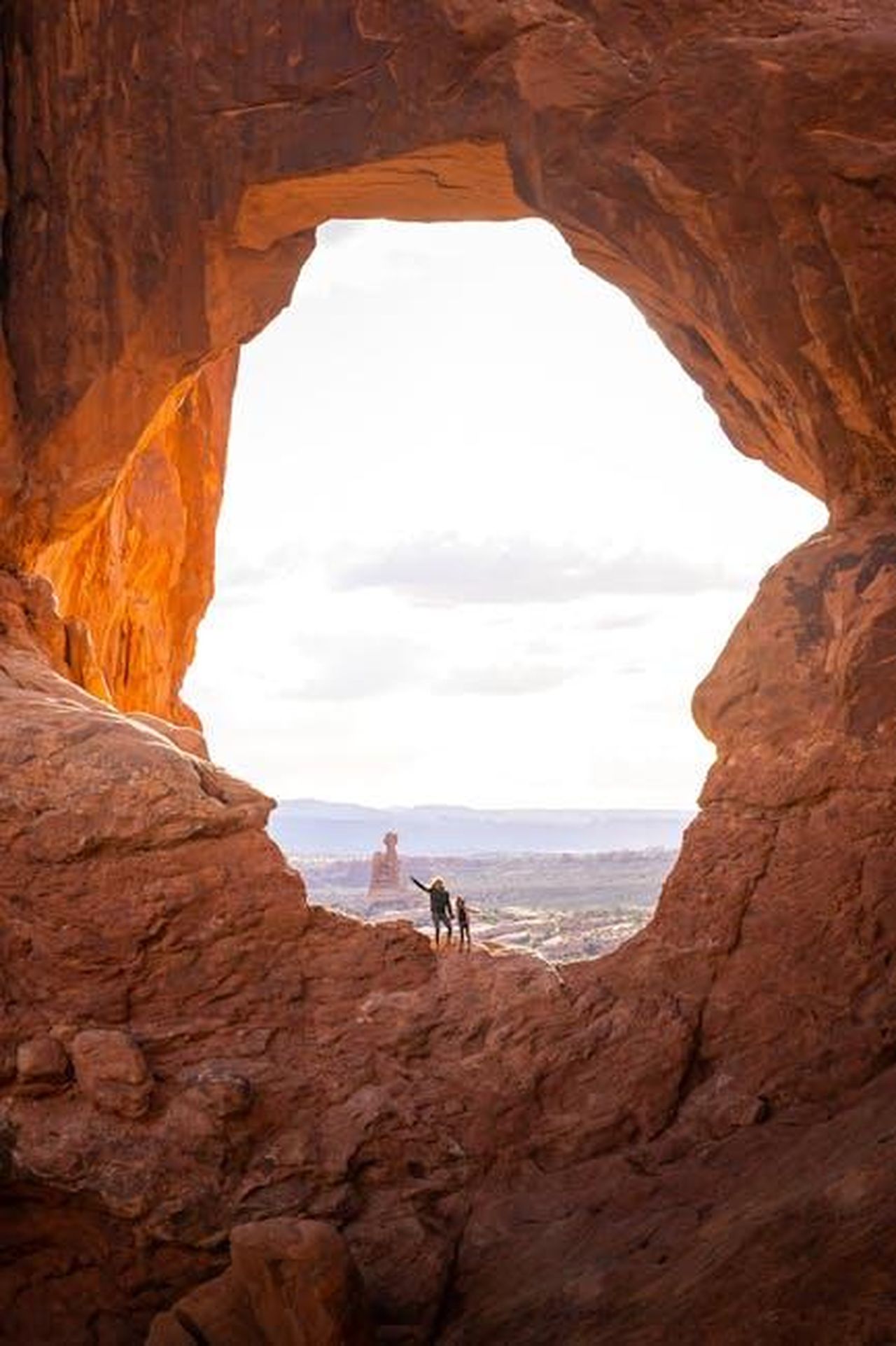 Source: Clément Proust - pexels - Hikers explore a sunlit natural arch in the stunning Arches National Park.