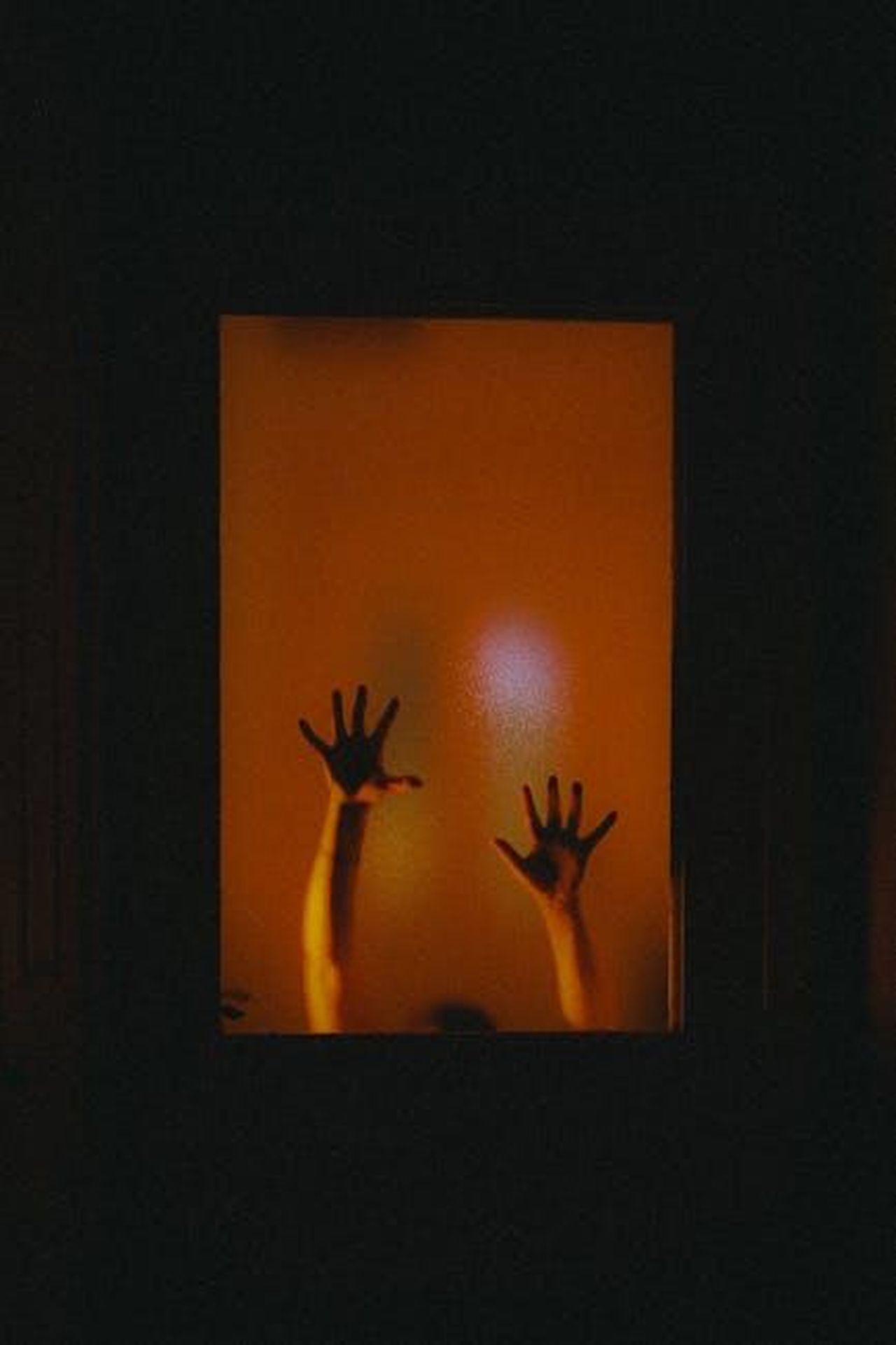 Source: Nathan J Hilton - pexels - Mysterious silhouette of raised hands behind frosted glass with a warm glow.