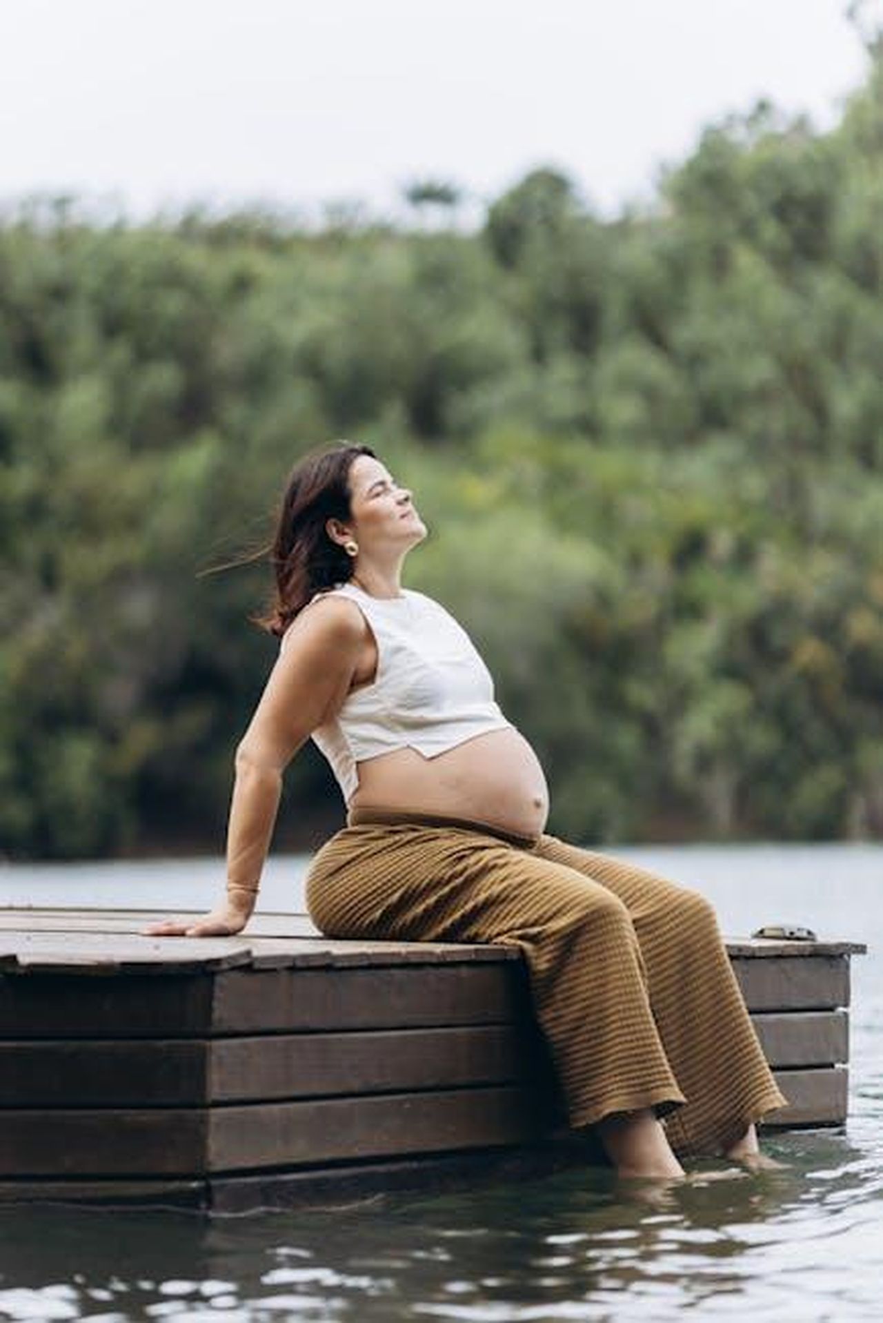 Source: Jonathan Borba - pexels - A serene moment of a pregnant woman enjoying nature by a lake.