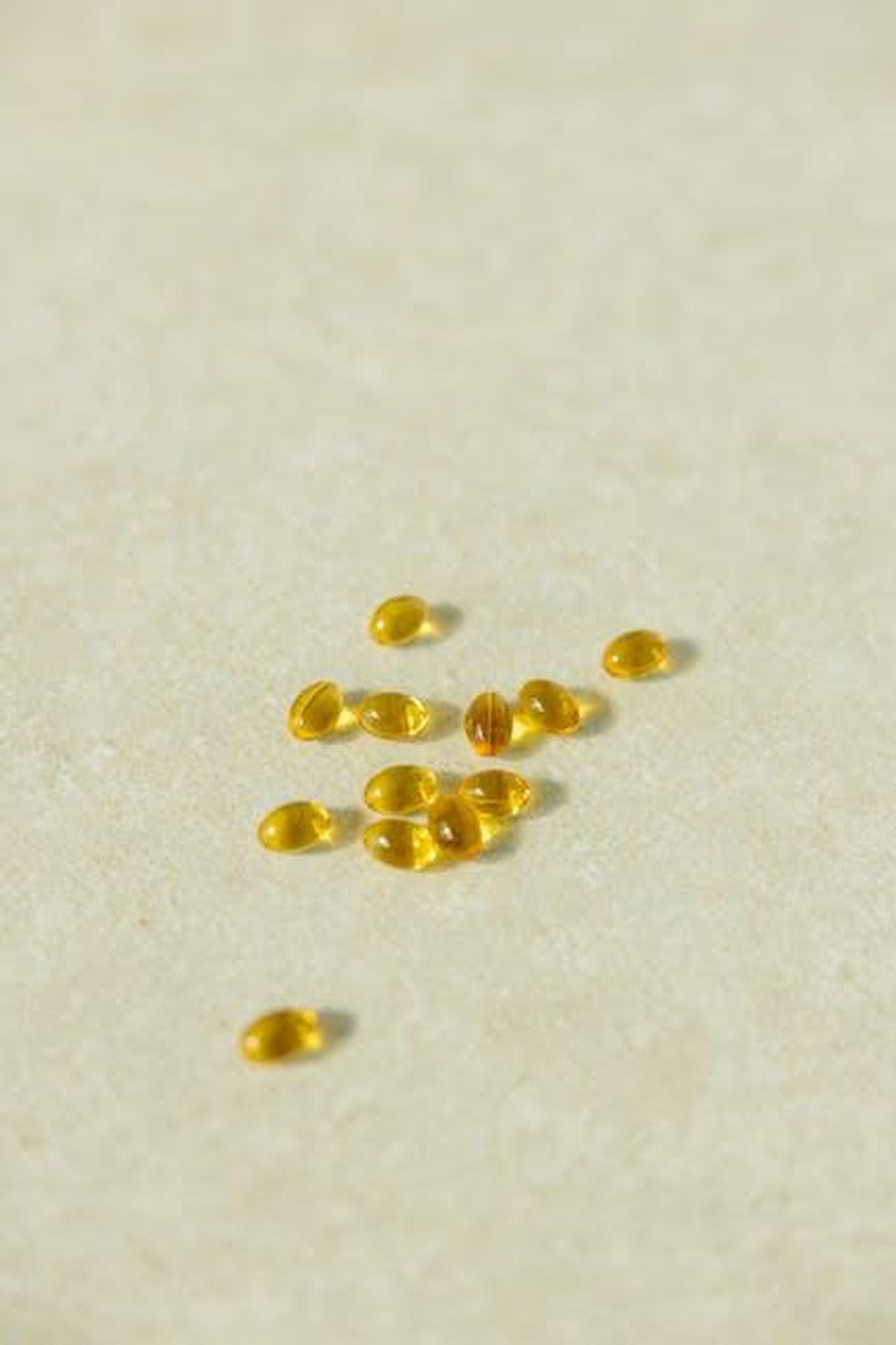 Source: Yaroslav Shuraev - pexels - A collection of transparent golden capsules arranged on a neutral light background depicting supplements or vitamins.