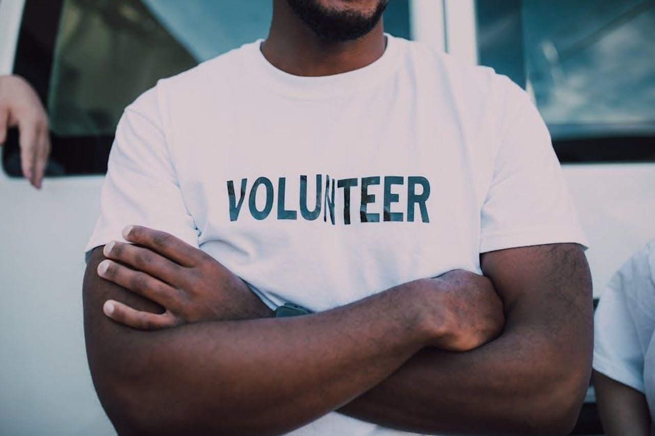 Source: RDNE Stock project - pexels - A close-up of a person wearing a volunteer shirt with arms crossed, promoting community service.
