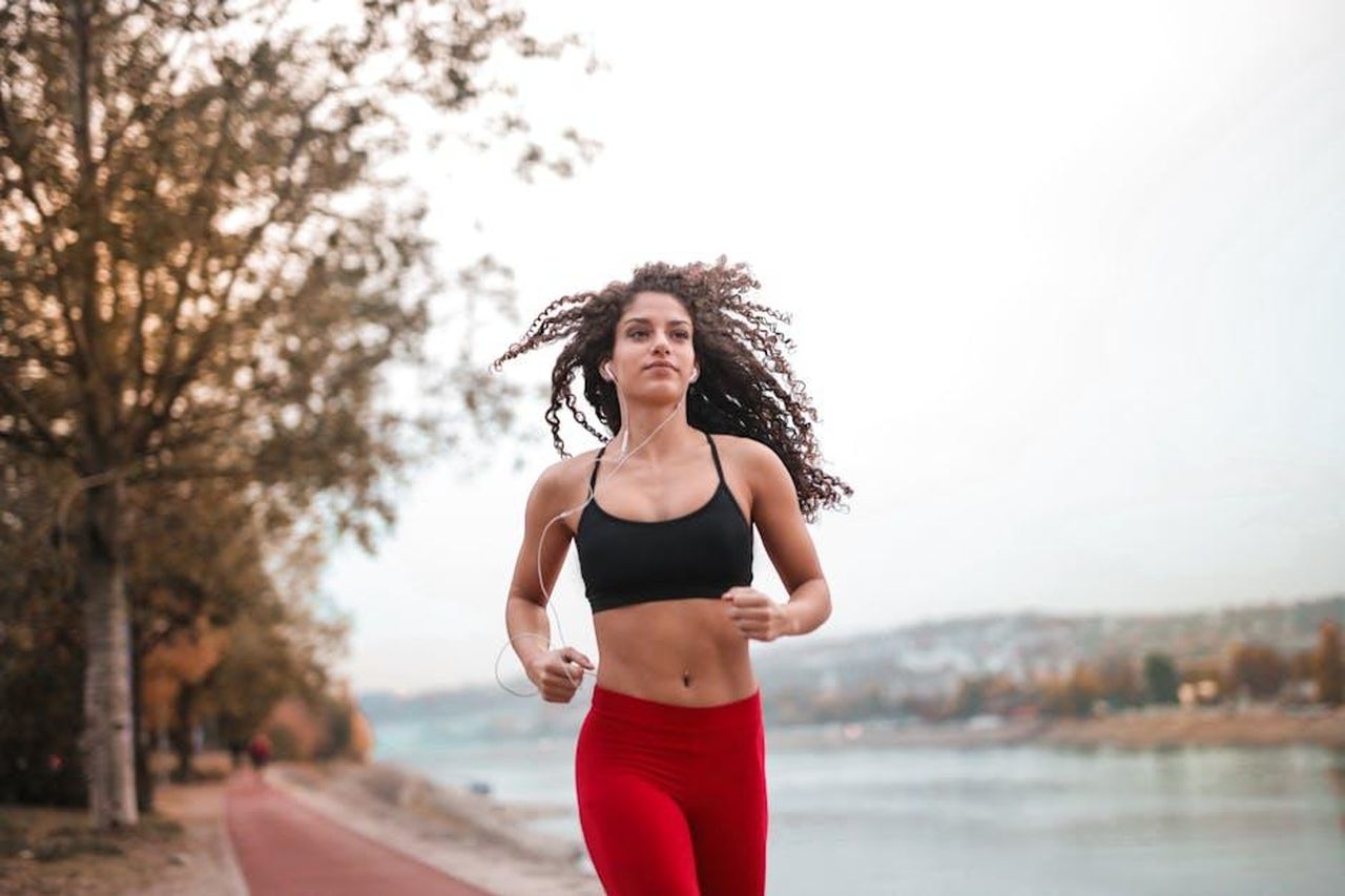 Source: Andrea Piacquadio - pexels - Determined woman in red leggings jogging along a scenic riverside path, embracing fitness outdoors.