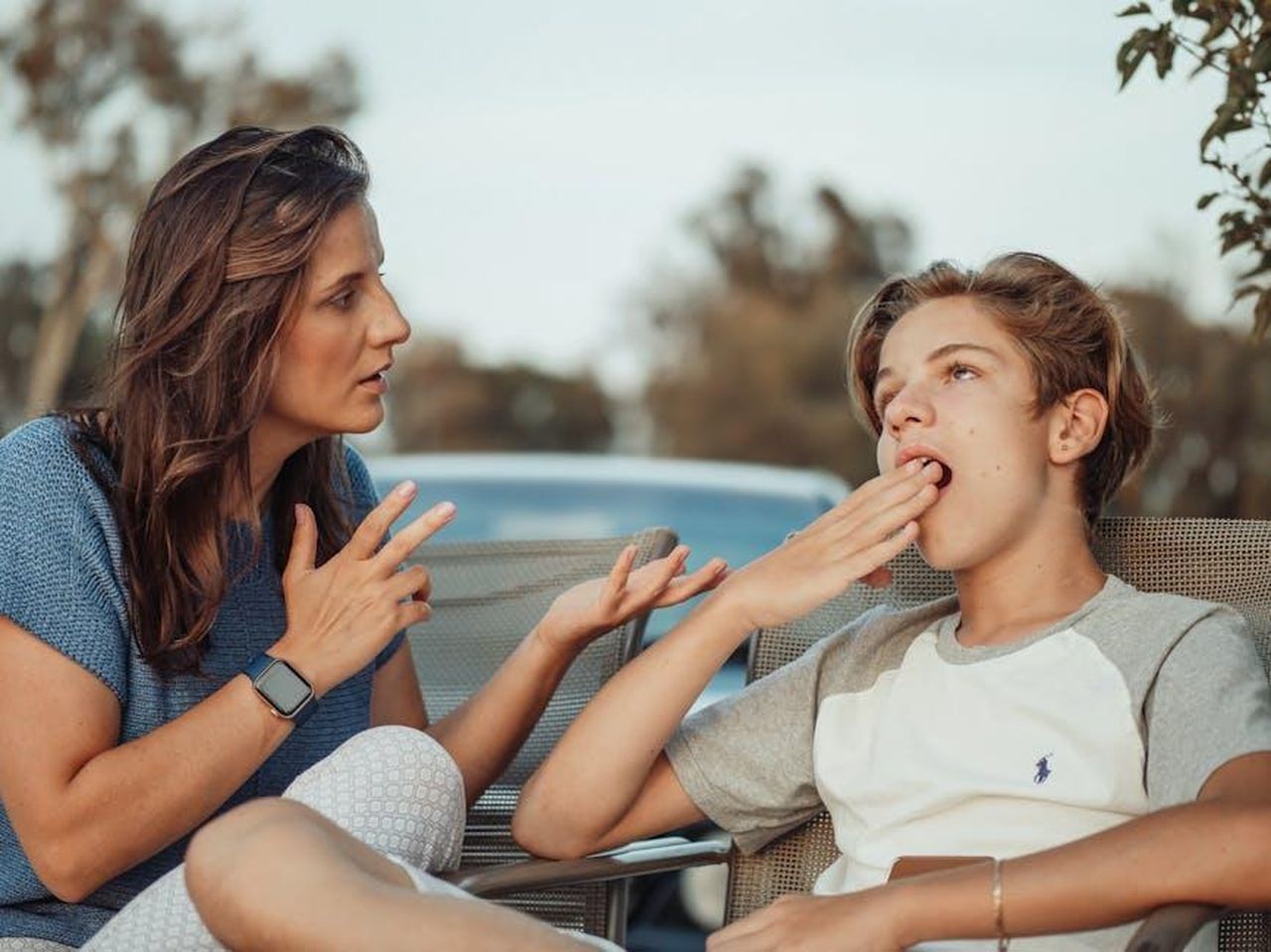 Source: Kindel Media - pexels - A mother and her teenage son are having a conversation outdoors. The son appears disinterested.