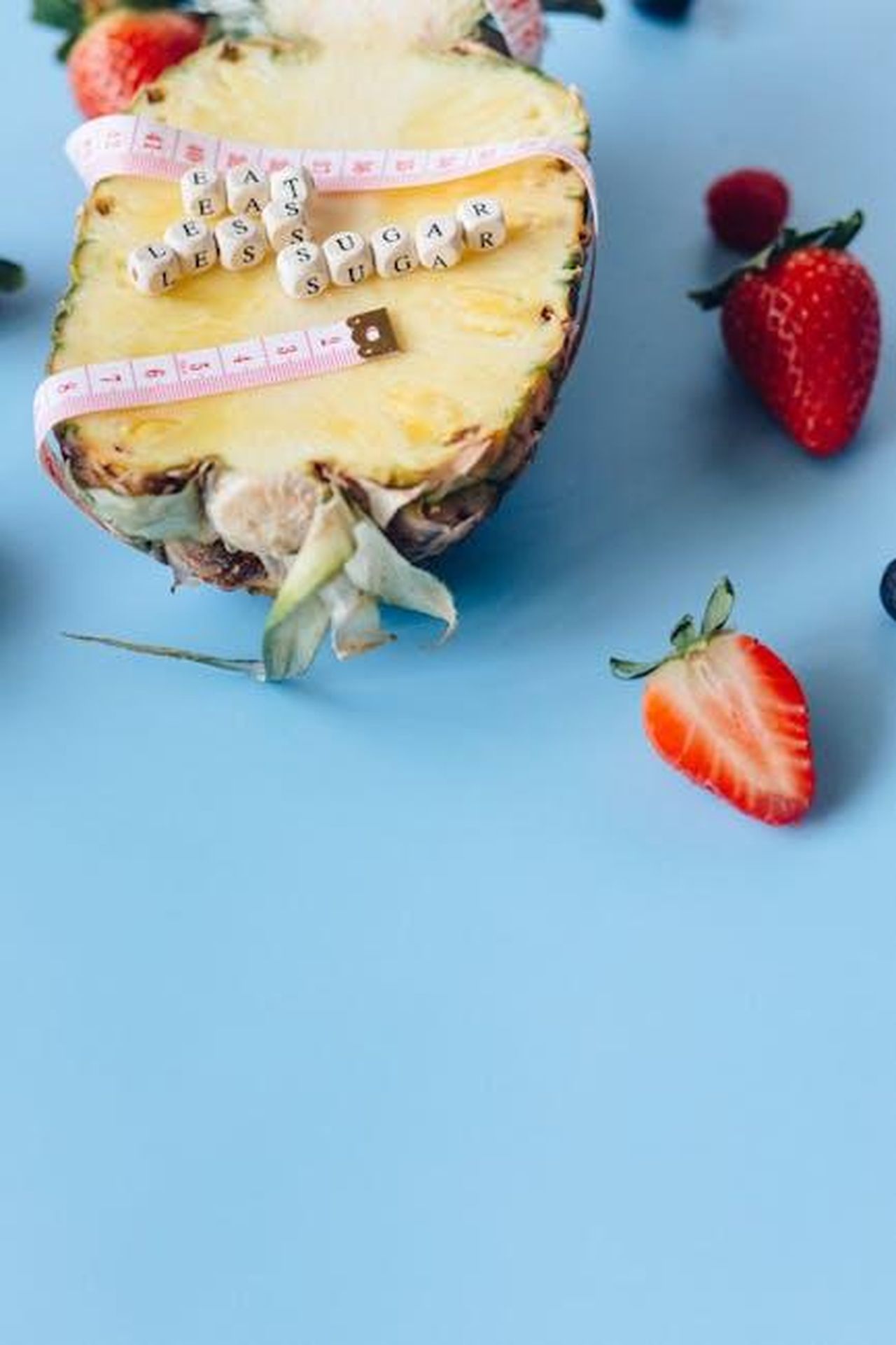Source: Nataliya Vaitkevich - pexels - Pineapple surrounded by berries with a health message promoting less sugar intake.