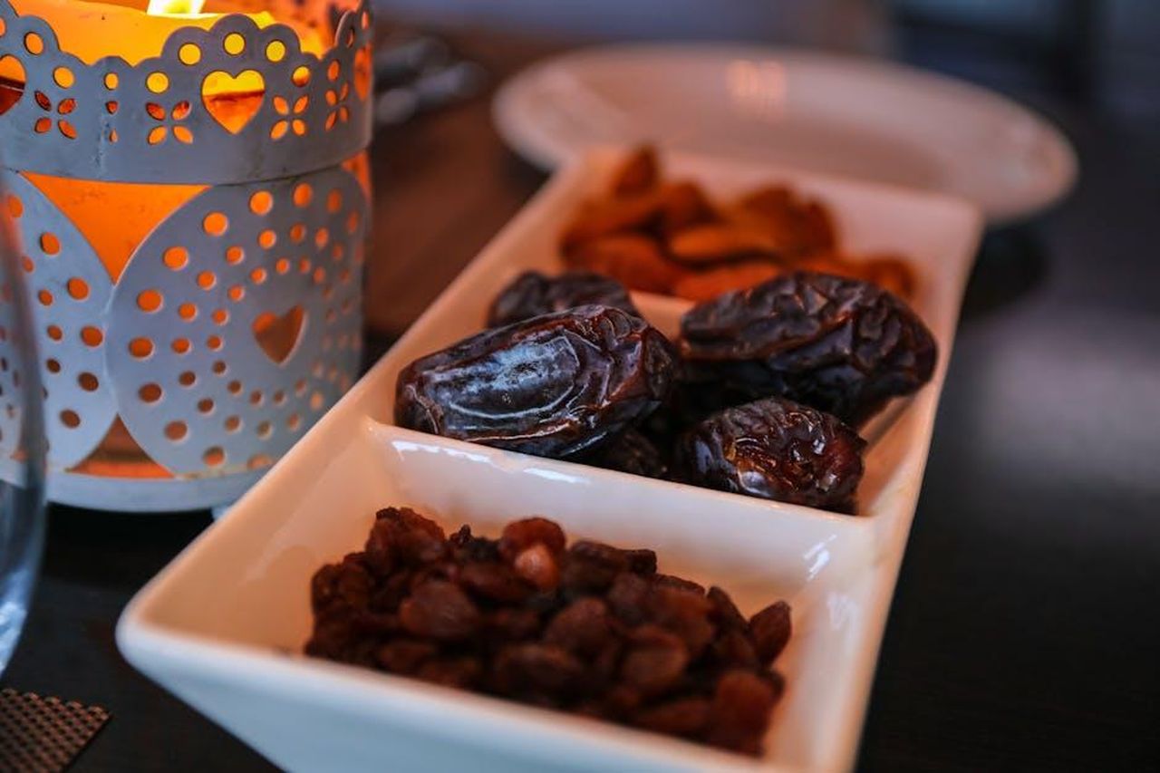 Source: Zak Chapman - pexels - Close-up of dried dates and lantern symbolizing Ramadan traditions. Ideal for festive themes.