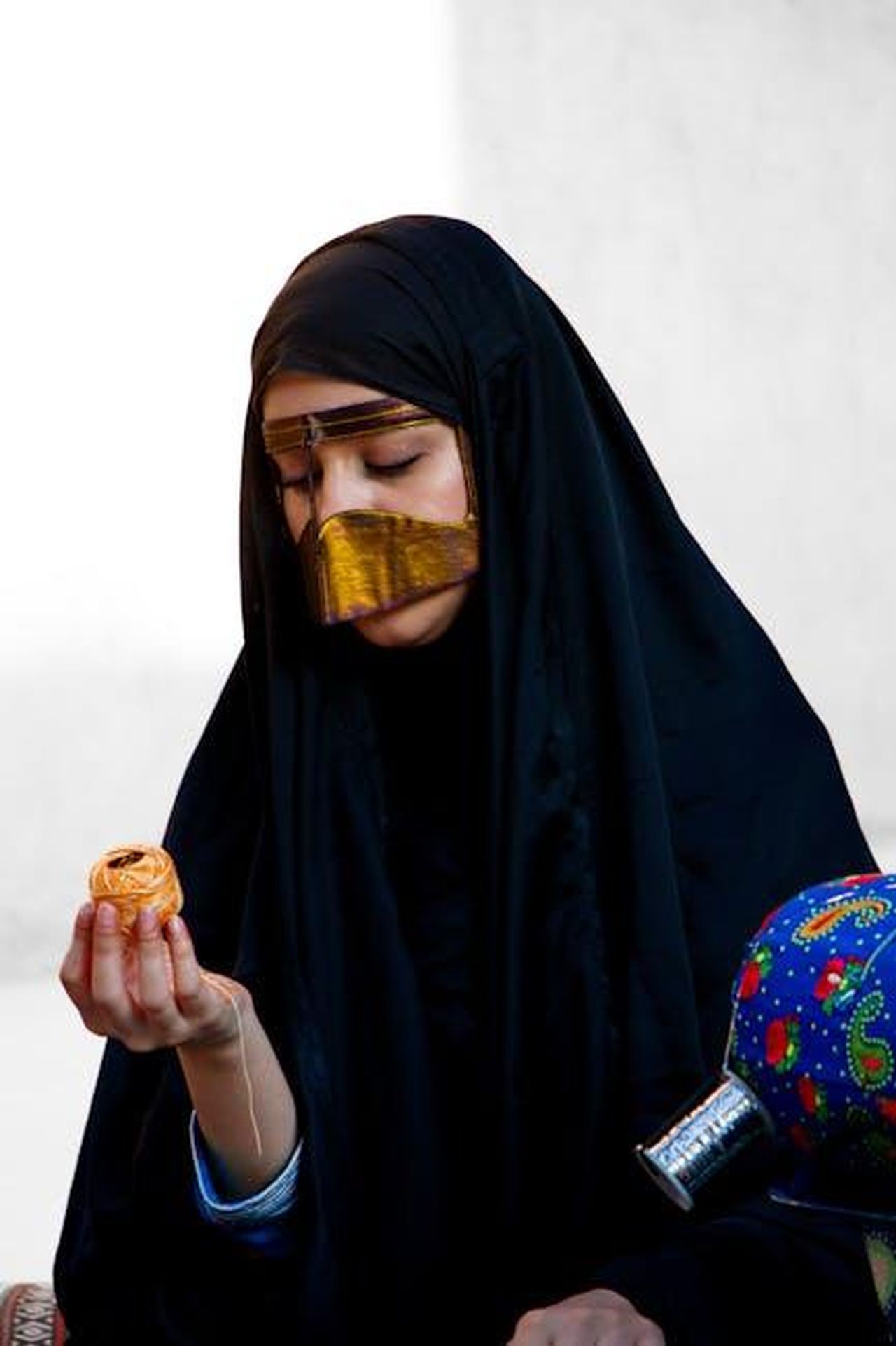 Source: Omar Rehan Khan - pexels - A woman in traditional Emirati attire holding a cultural artifact in Dubai, UAE.