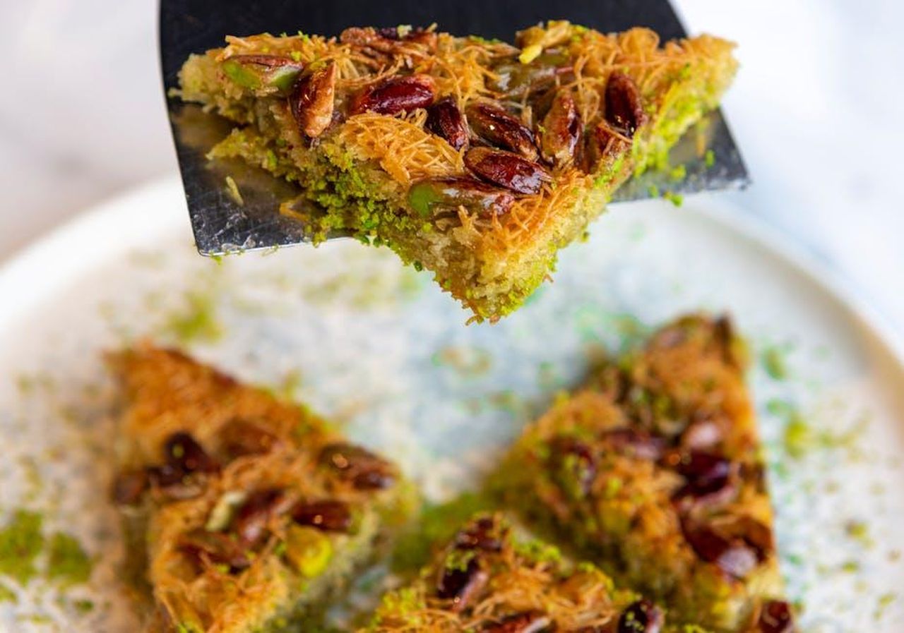 Source: Hkn clk - pexels - Close-up of a pistachio and almond baklava slice on a spatula, showcasing its texture.