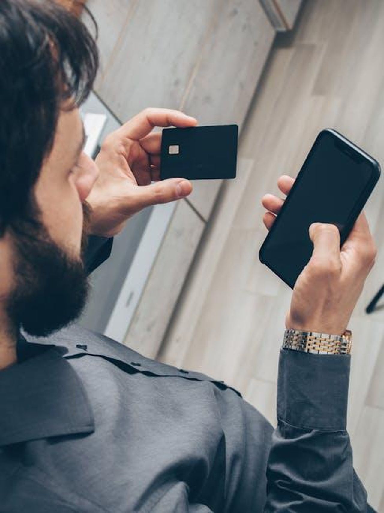 Source: Mikhail Nilov - pexels - Adult man using a smartphone for online transactions while holding a credit card indoors.