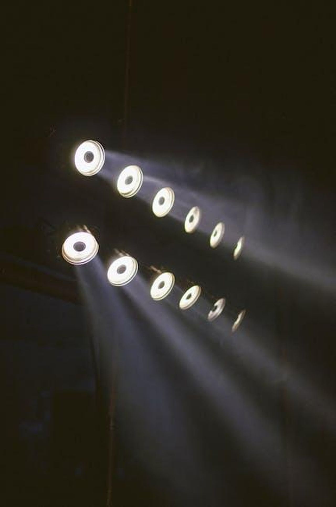 Source: Isabella Mendes - pexels - Array of LED lights casting beams in a dark, moody industrial space.