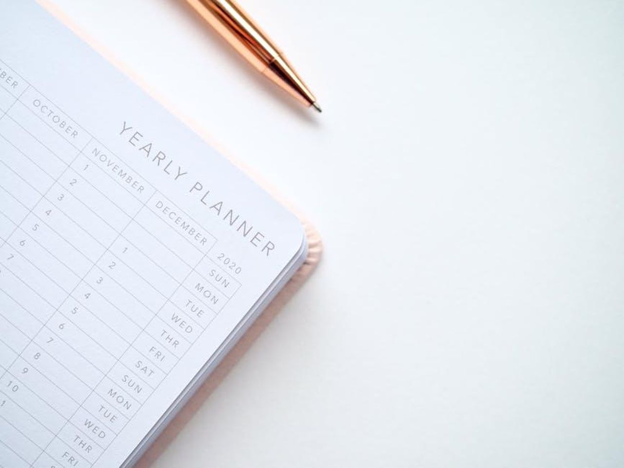 Source: Jess Bailey Designs - pexels - A stylish yearly planner open to a 2020 calendar page, accompanied by a golden pen on a clean white surface.