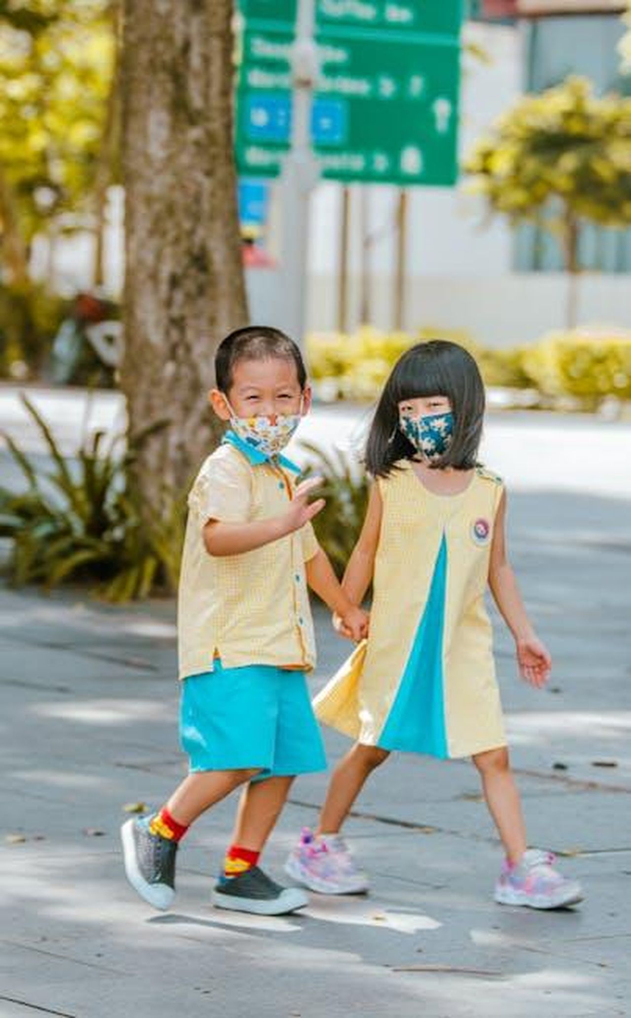 Source: Christian Alemu - pexels - Two children in colorful clothes and masks walk hand in hand in an outdoor setting, showing friendship and safety.