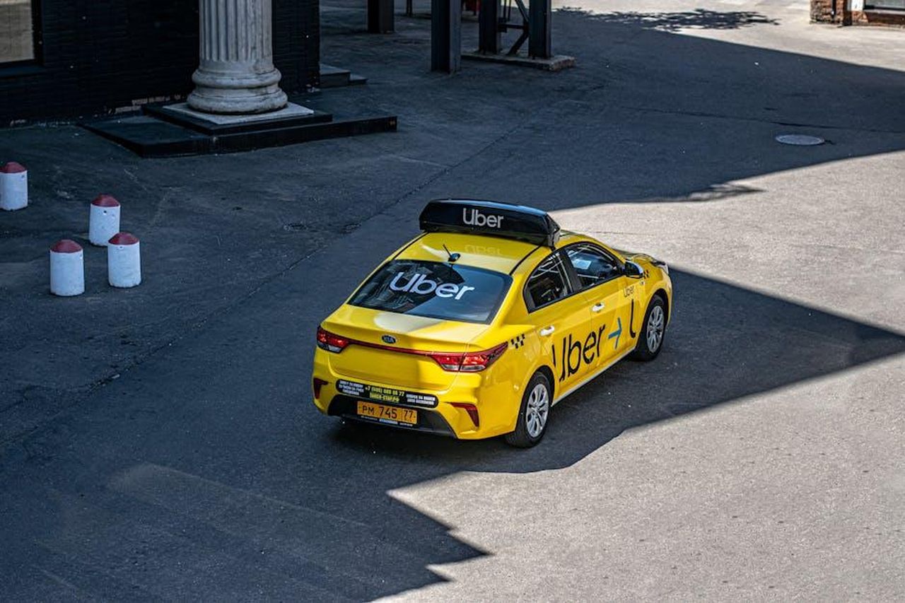Source: Aleksandr Sochnev - pexels - A yellow Uber taxi driving on a city street, shown from above.