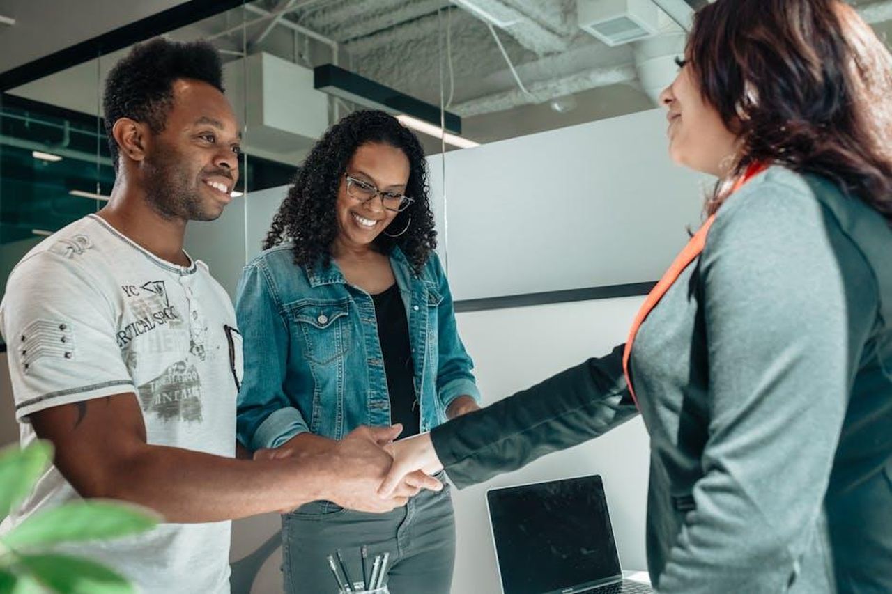 Source: Kindel Media - pexels - Smiling couple shaking hands with advisor in modern office.
