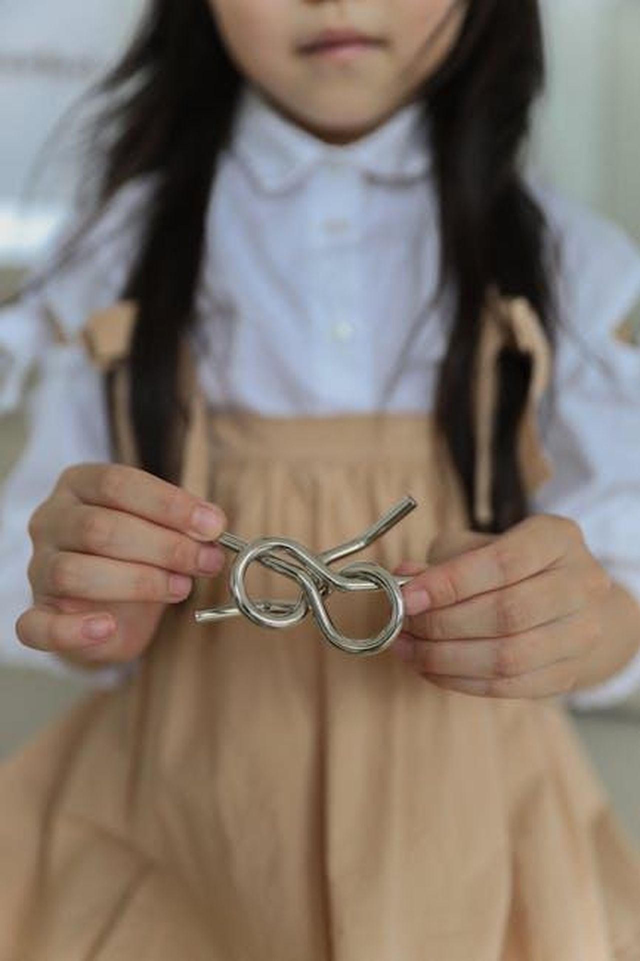 Source: Monstera Production - pexels - Crop faceless child in casual clothes holding metal wire brain teaser while playing at home