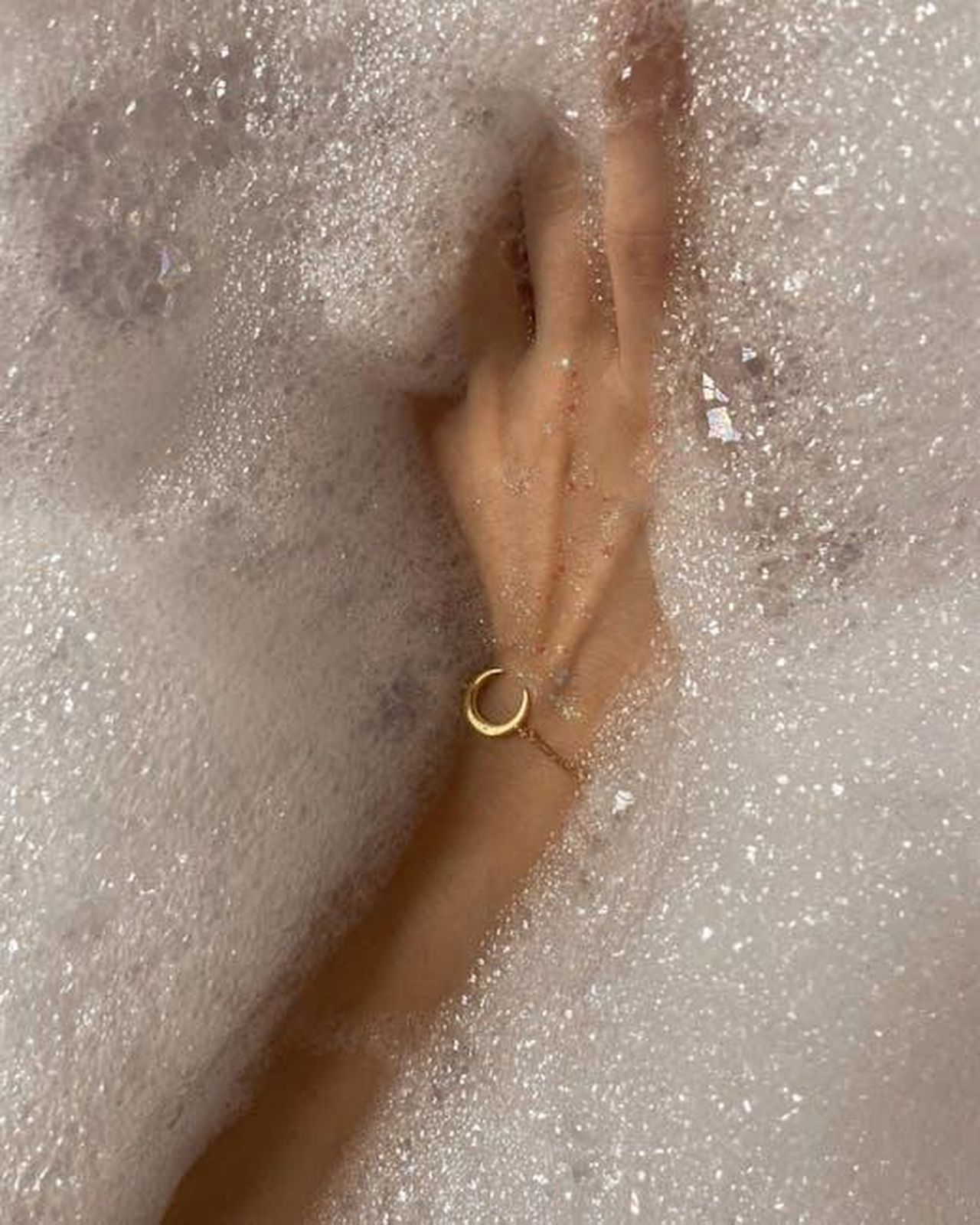 Source: Mariam Antadze - pexels - A woman's hand with a bracelet submerged in a bubbly bathtub, capturing serenity and self-care.