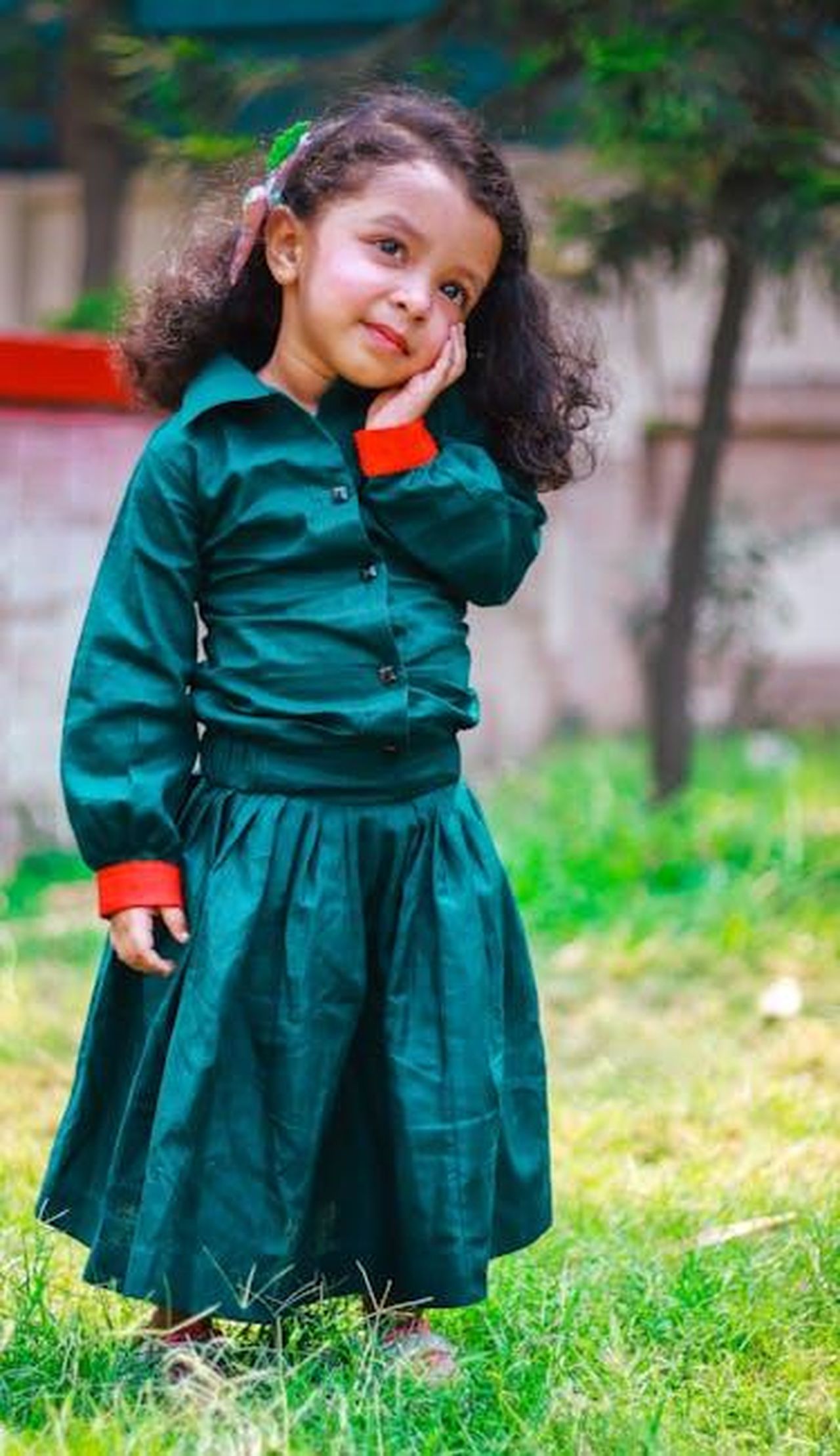 Source: Focus Cam photography - pexels - Charming young girl in a green dress posing in a garden, showcasing innocence and joy.