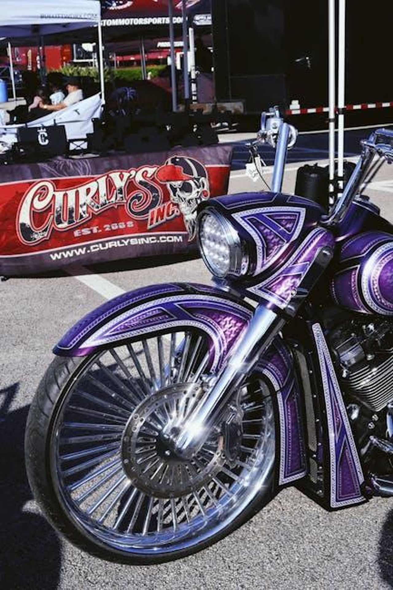 Source: Nastya Gold - pexels - Stunning purple custom motorcycle displayed at an outdoor auto event.