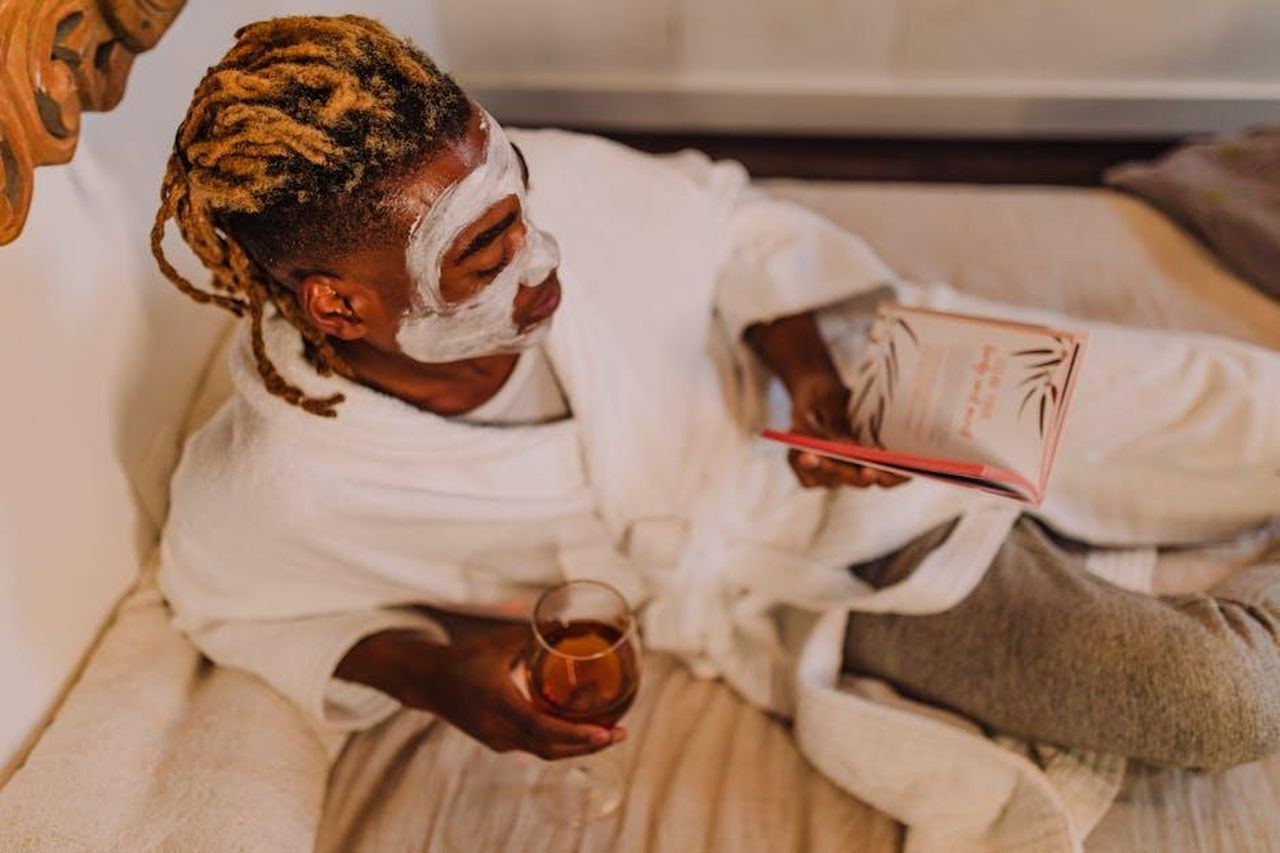 Source: RDNE Stock project - pexels - A person enjoying a spa day with a facial mask, book, and wine, embodying relaxation.
