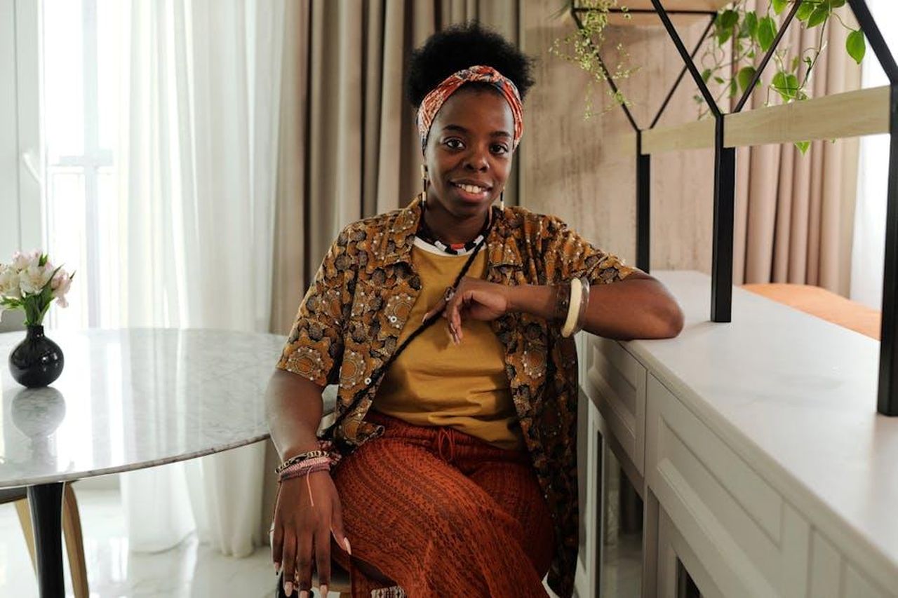 Source: Diva Plavalaguna - pexels - A smiling woman sits relaxed indoors, creating a warm and inviting atmosphere.
