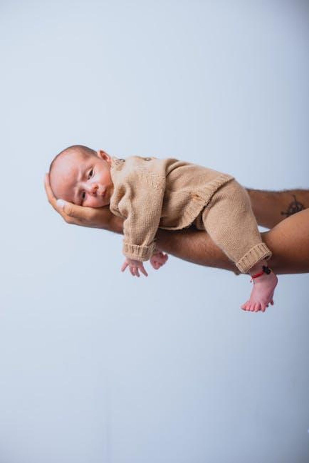 Source: Norman Milwood - pexels - A newborn baby lies safely supported by a hand, creating a tender moment.