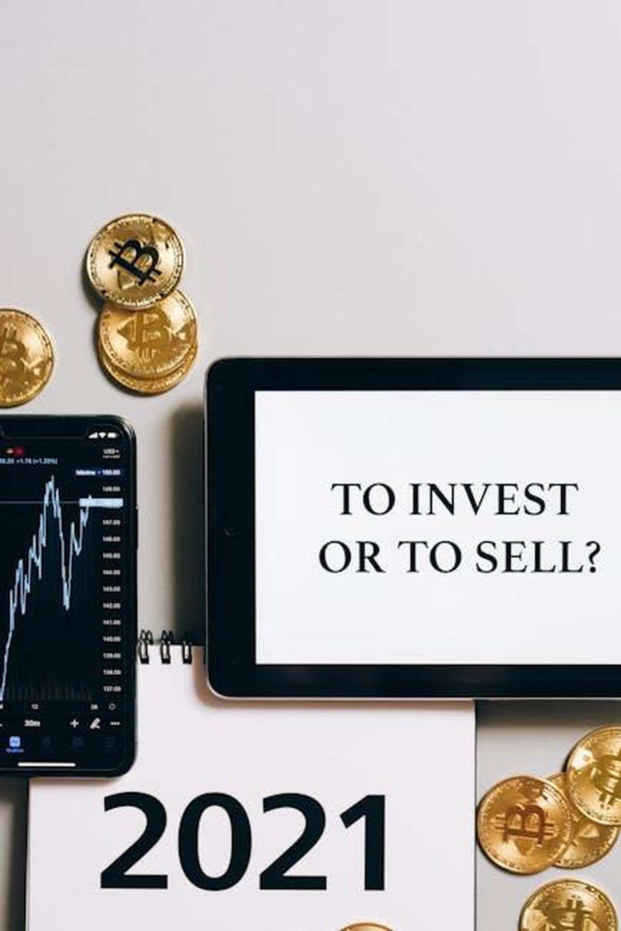 Source: Leeloo The First - pexels - Tablet with 'To Invest or To Sell?' text, gold bitcoins, smartphone displaying a stock chart.