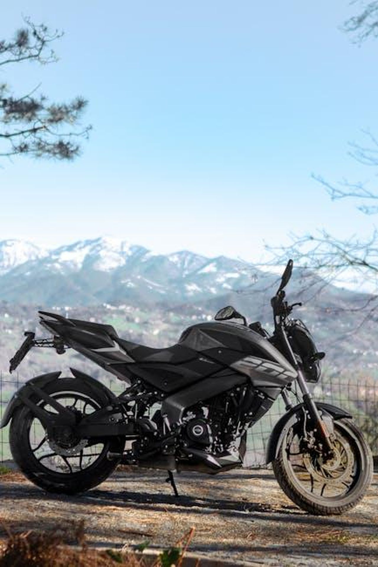 Source: Bedir Dalbay - pexels - Black motorcycle parked with snowy mountain backdrop in daylight.