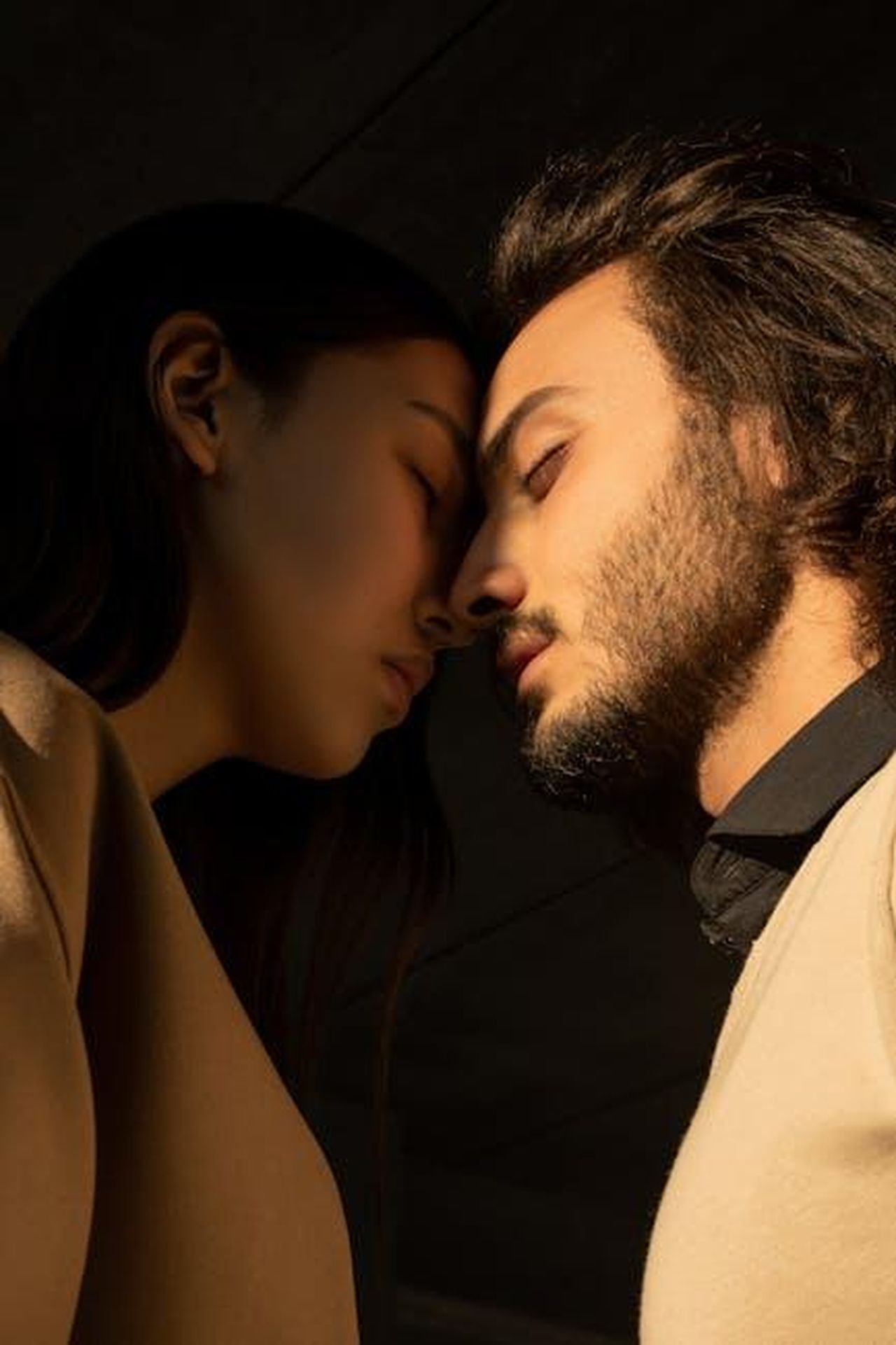 Source: Ba Tik - pexels - Side view of a couple sharing an intimate moment with closed eyes under soft lighting.