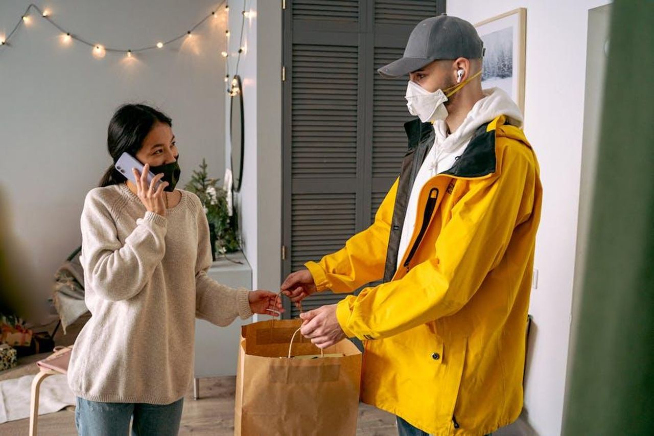Source: Antoni Shkraba - pexels - A woman receives a delivery in a contactless manner, showcasing modern safety practices.