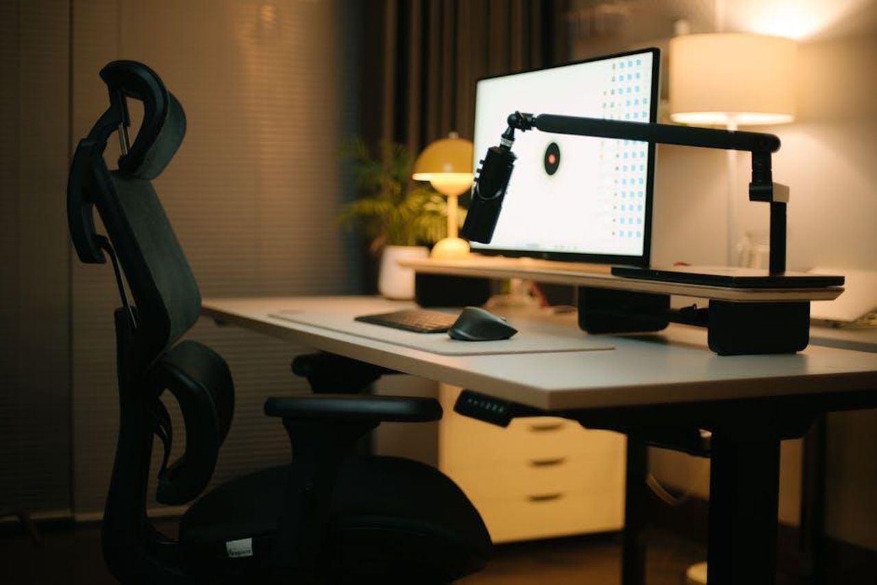 Source: Alpha En - pexels - A cozy home office featuring an ergonomic chair, computer setup, and ambient lighting for a productive environment.