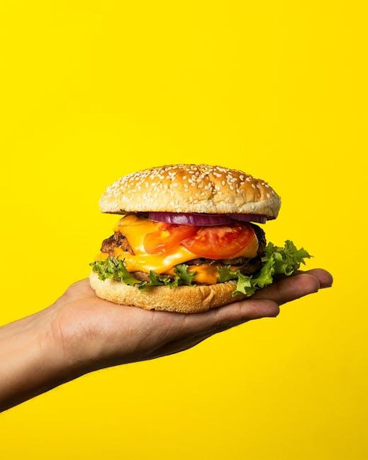 Source: José Pérez (Artesano) - pexels - Juicy cheeseburger with fresh toppings on a vibrant yellow background.