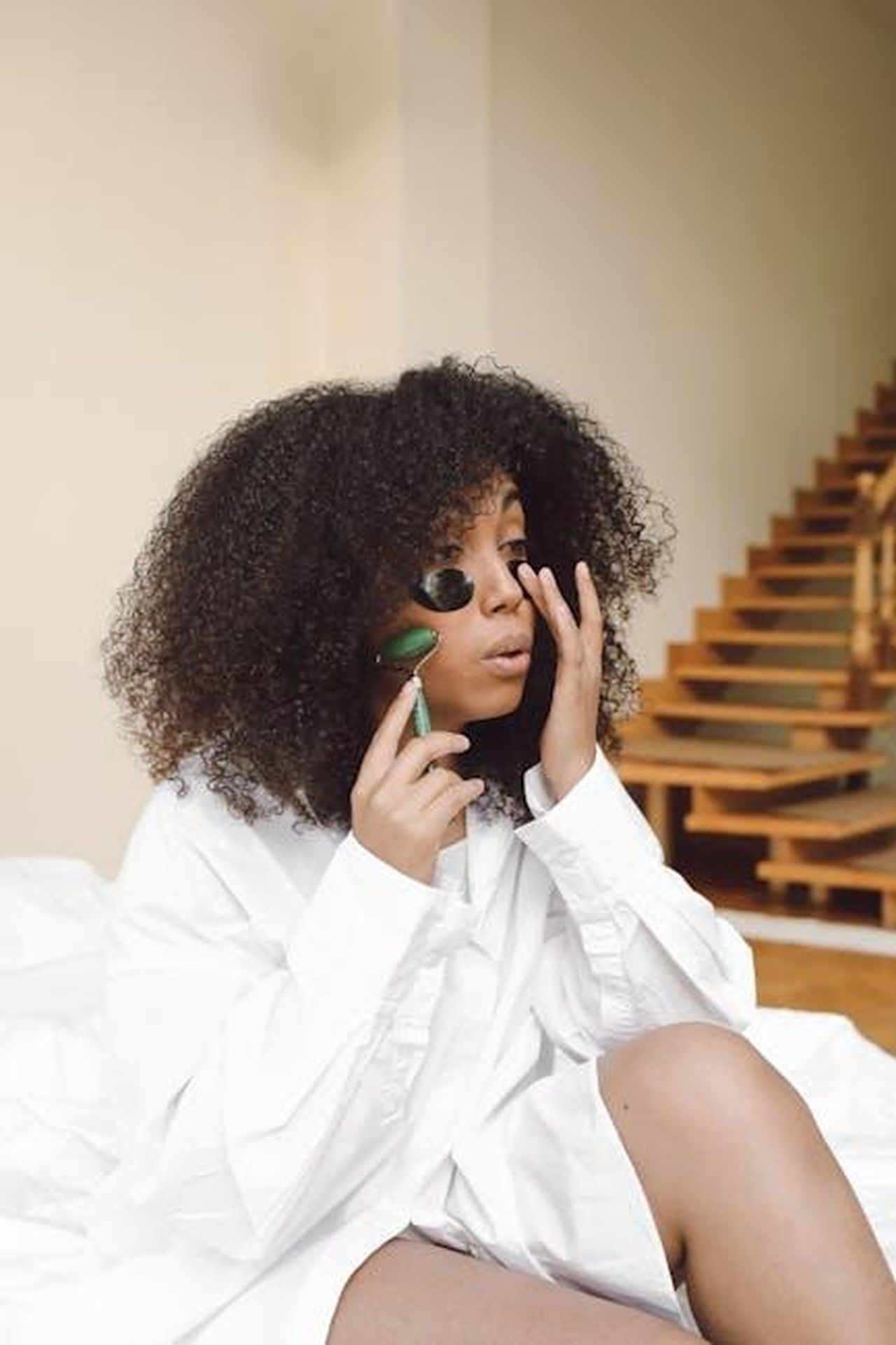 Source: Polina Tankilevitch - pexels - African American woman using jade roller for self-care in a cozy indoor setting.