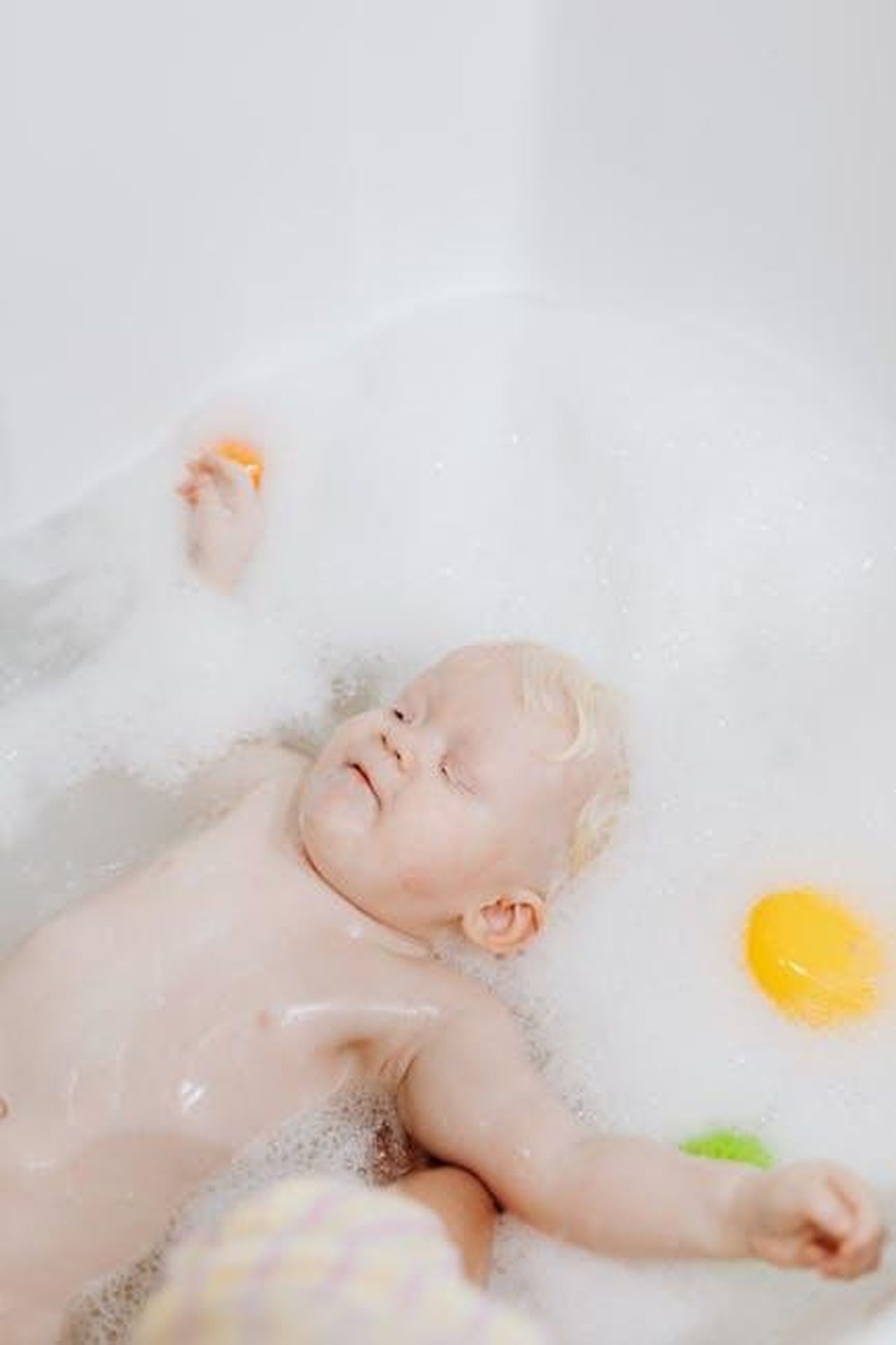 Source: Photo By: Kaboompics.com - pexels - A baby enjoying a bubble bath with colorful bath toys, conveying a sense of relaxation and playfulness.