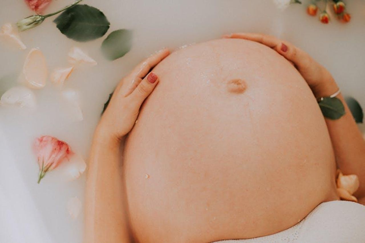 Source: lucas mendes - pexels - Pregnant woman relaxing in a soothing milk bath with flowers, embracing maternity.