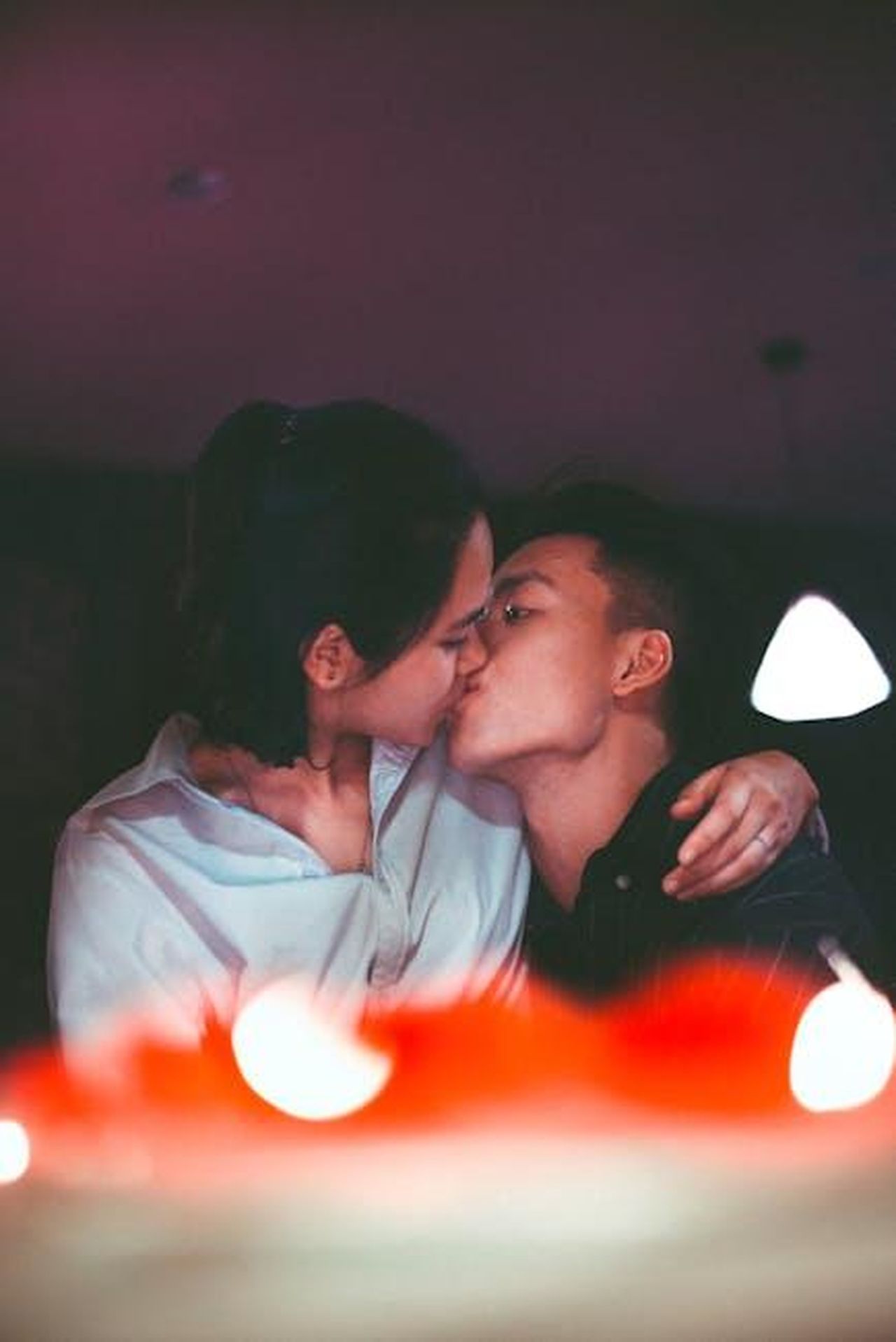Source: Tan Danh - pexels - A romantic kiss shared by an Asian couple, captured in a warm, intimate setting.